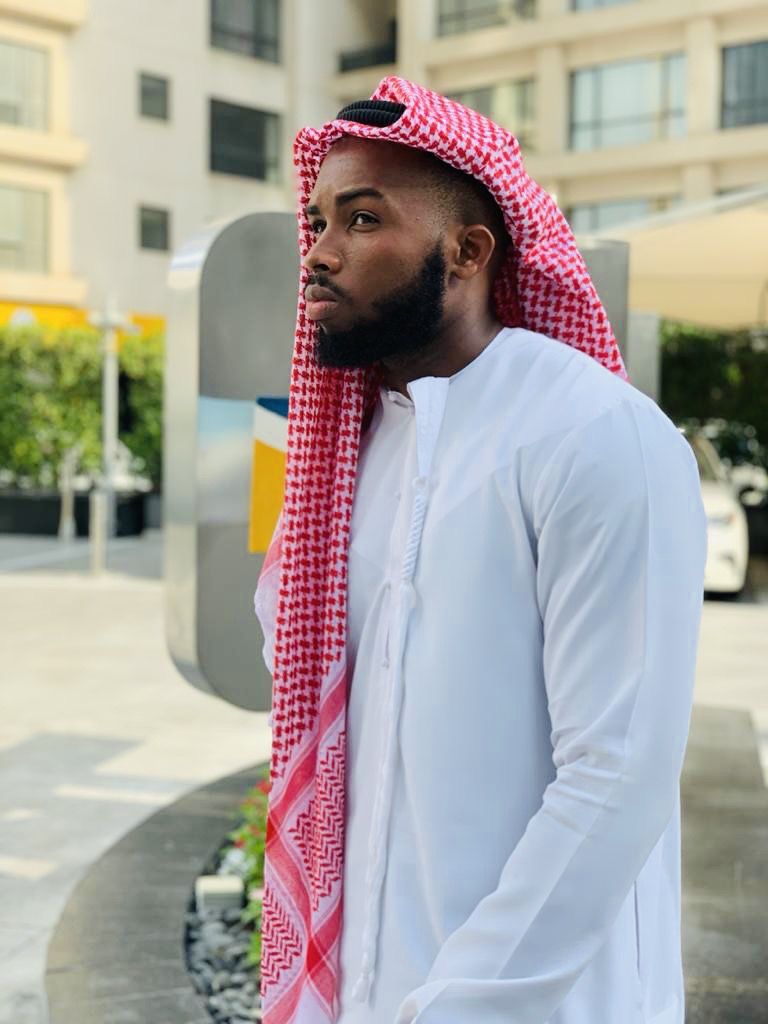 OJ in a white kandura and red checked shemagh on a city street