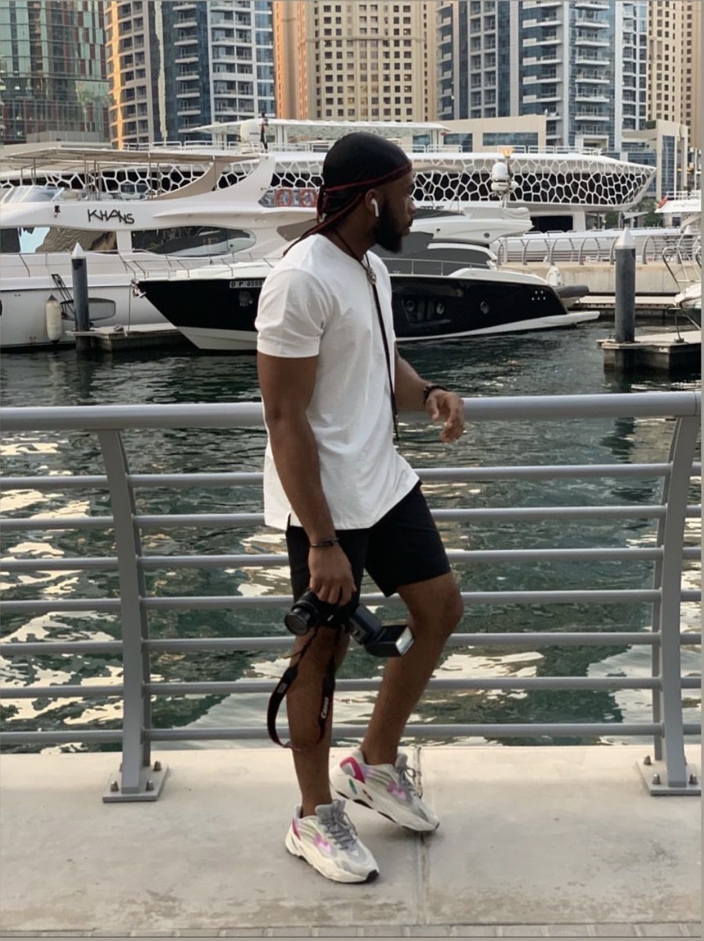OJ walking along the waterfront with yachts and towers behind, Dubai Marina