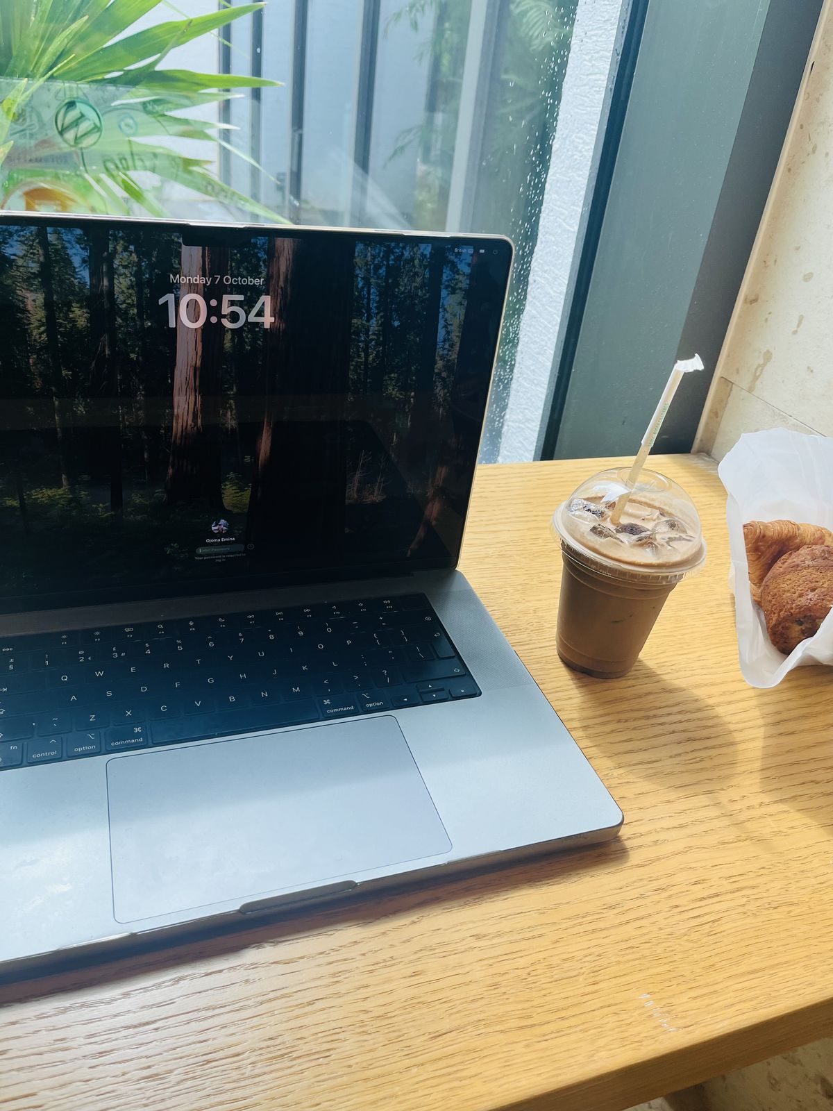 A laptop and iced coffee on a wooden table