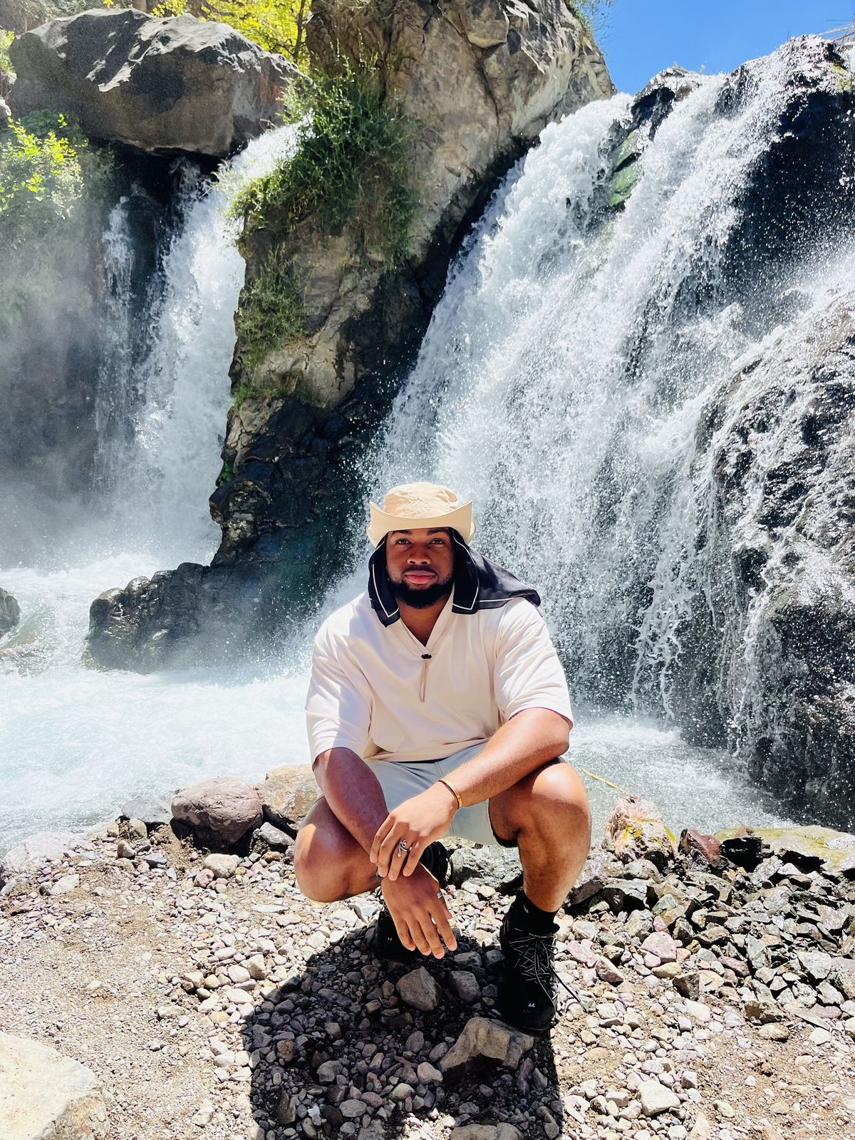 OJ crouching in front of a waterfall
