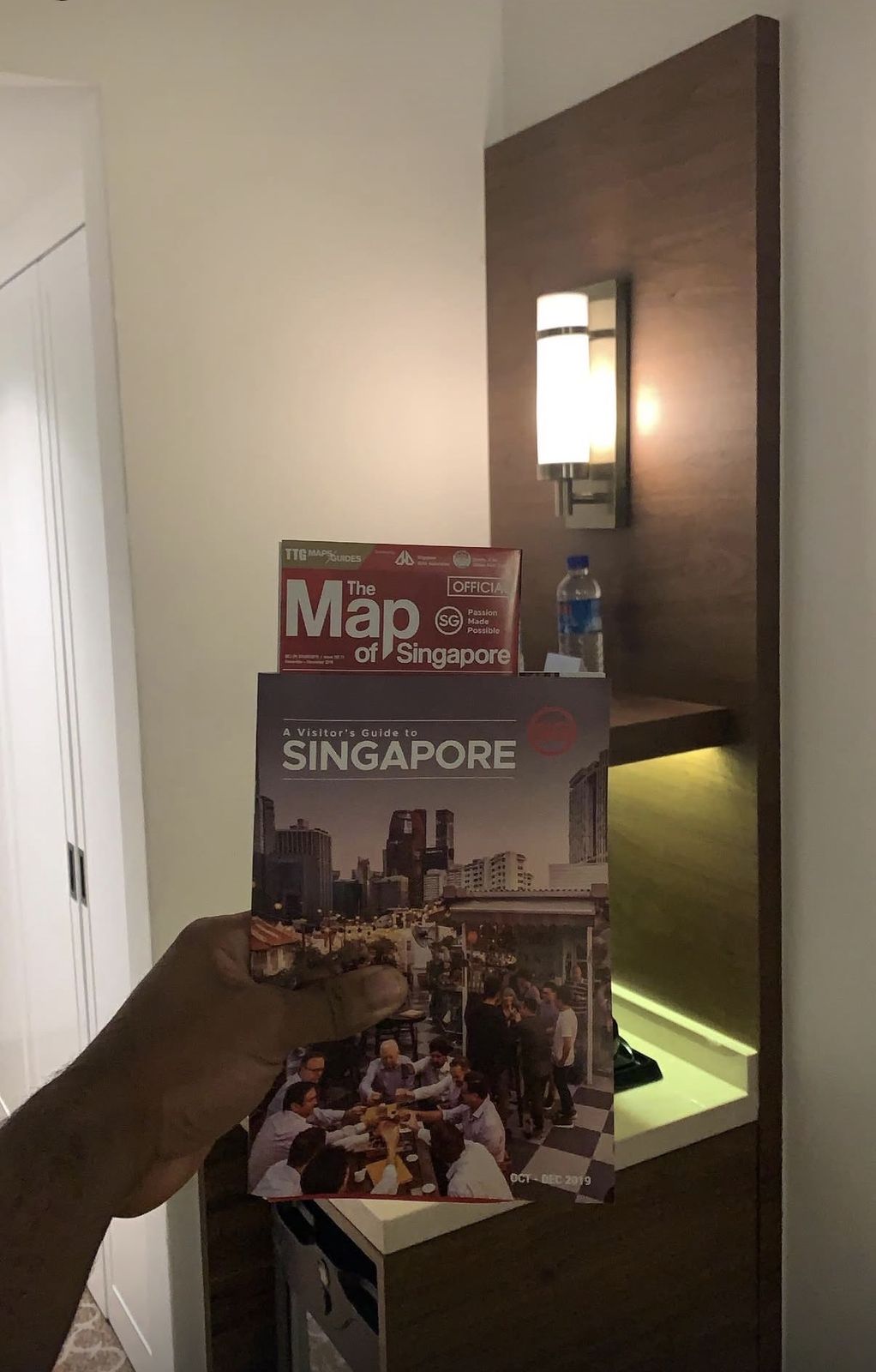 OJ's hand holding a Map of Singapore and a city guide