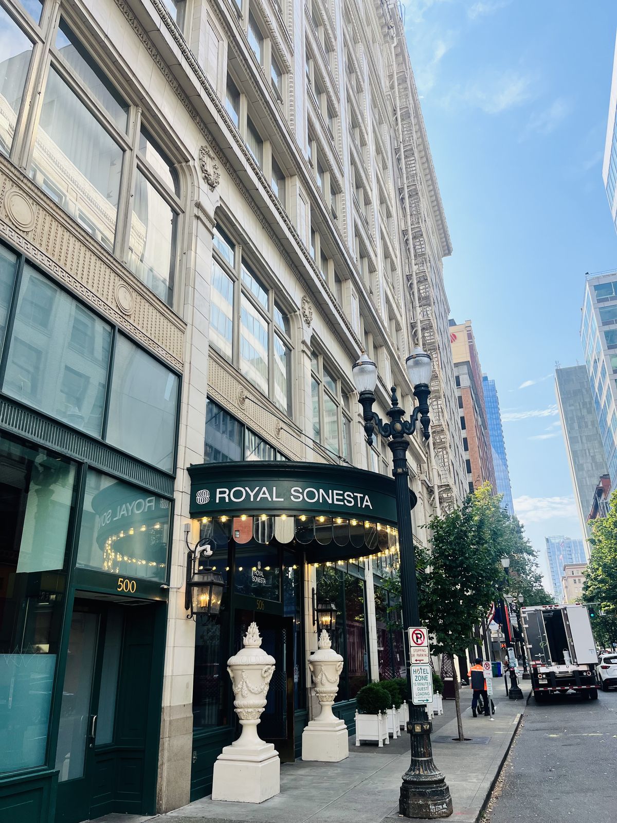 A tall downtown street with a hotel canopy