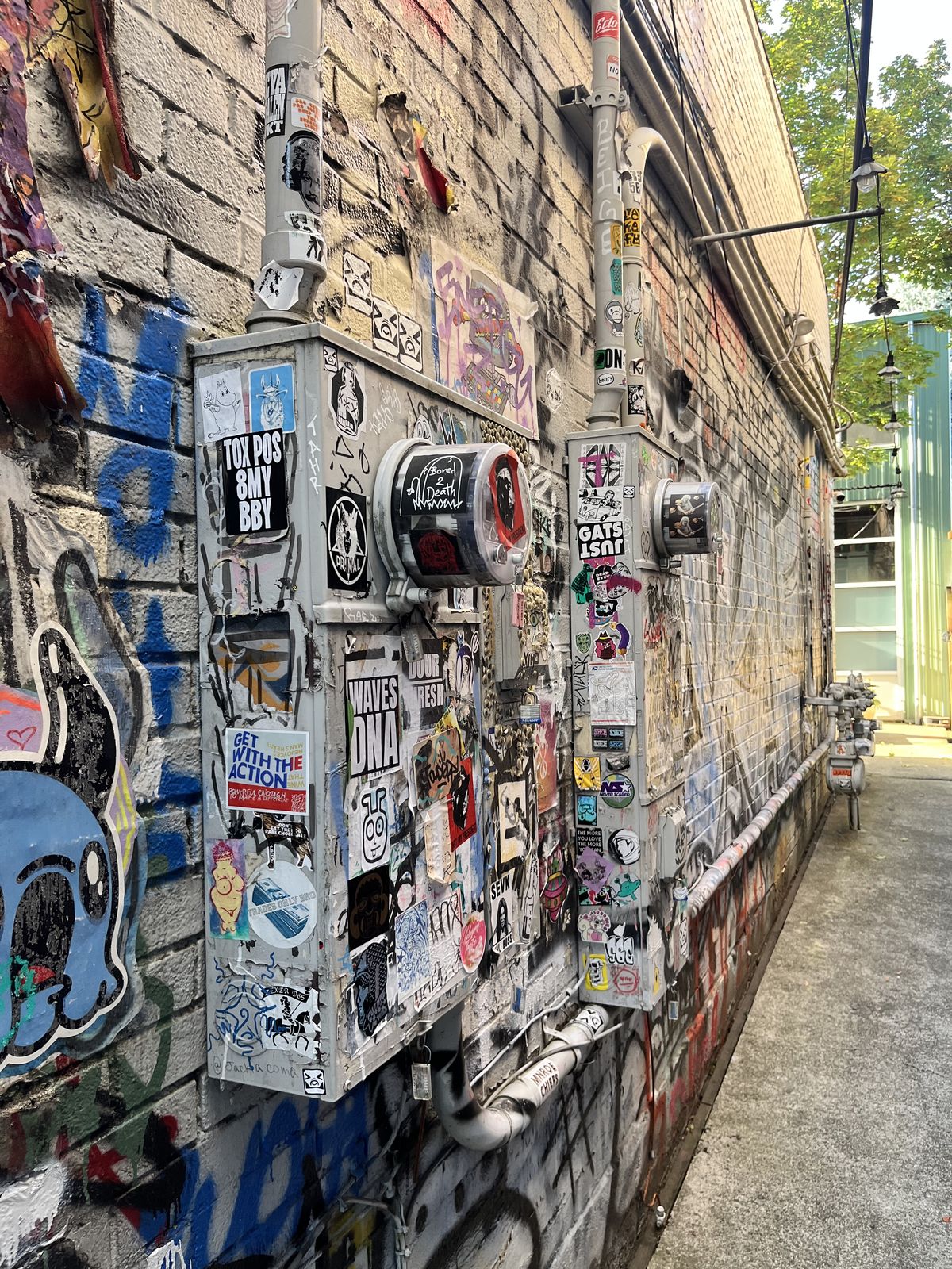 A wall of stickers and graffiti over old electrical boxes