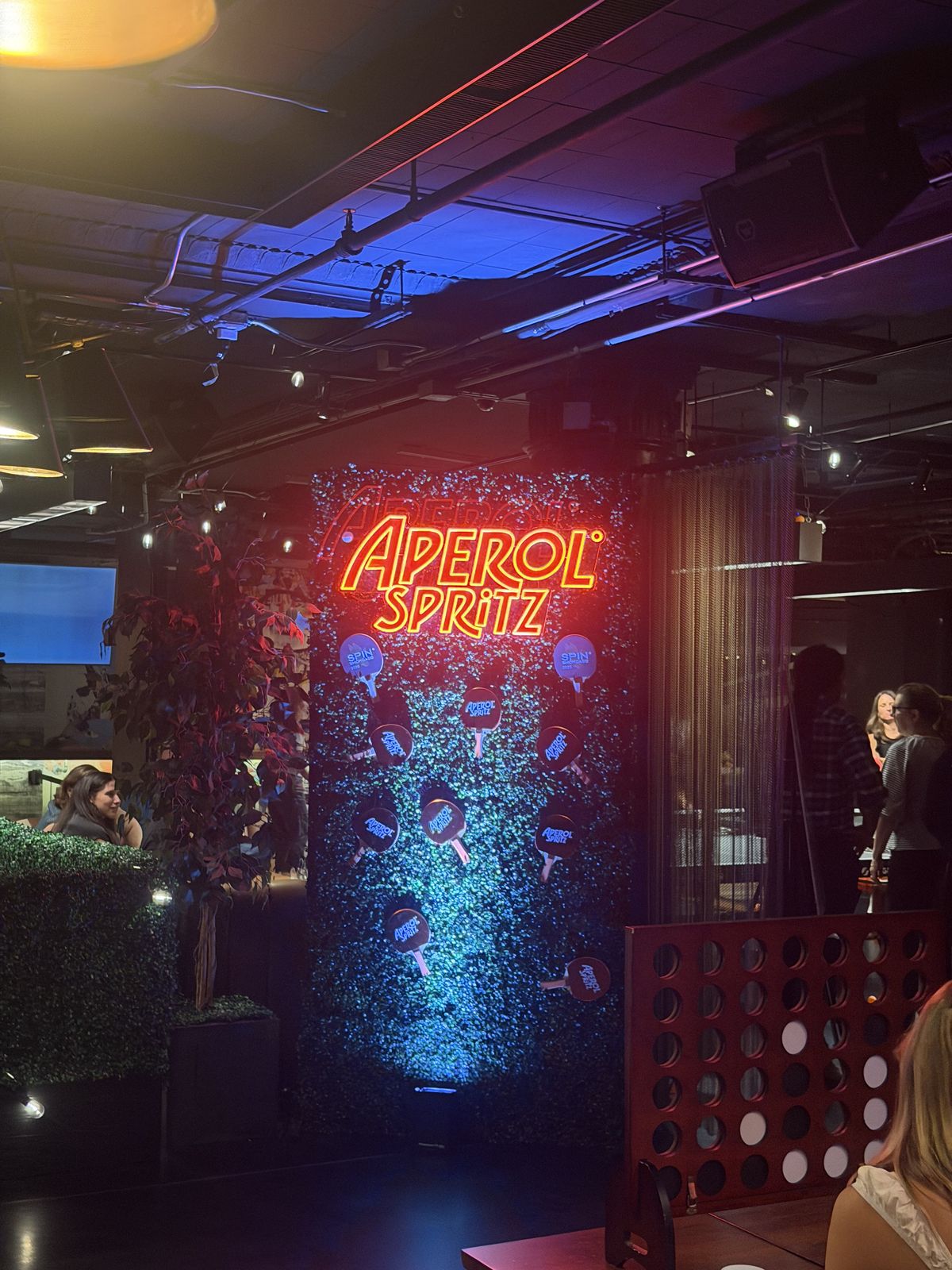 A neon Aperol Spritz sign in a dark bar